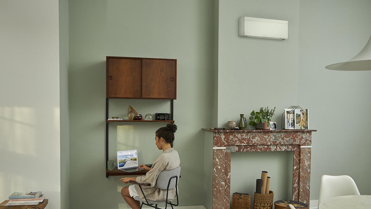 A calm living room shown twice, warm without an air conditioning unit and cool with a slim unit fitted high on the wall